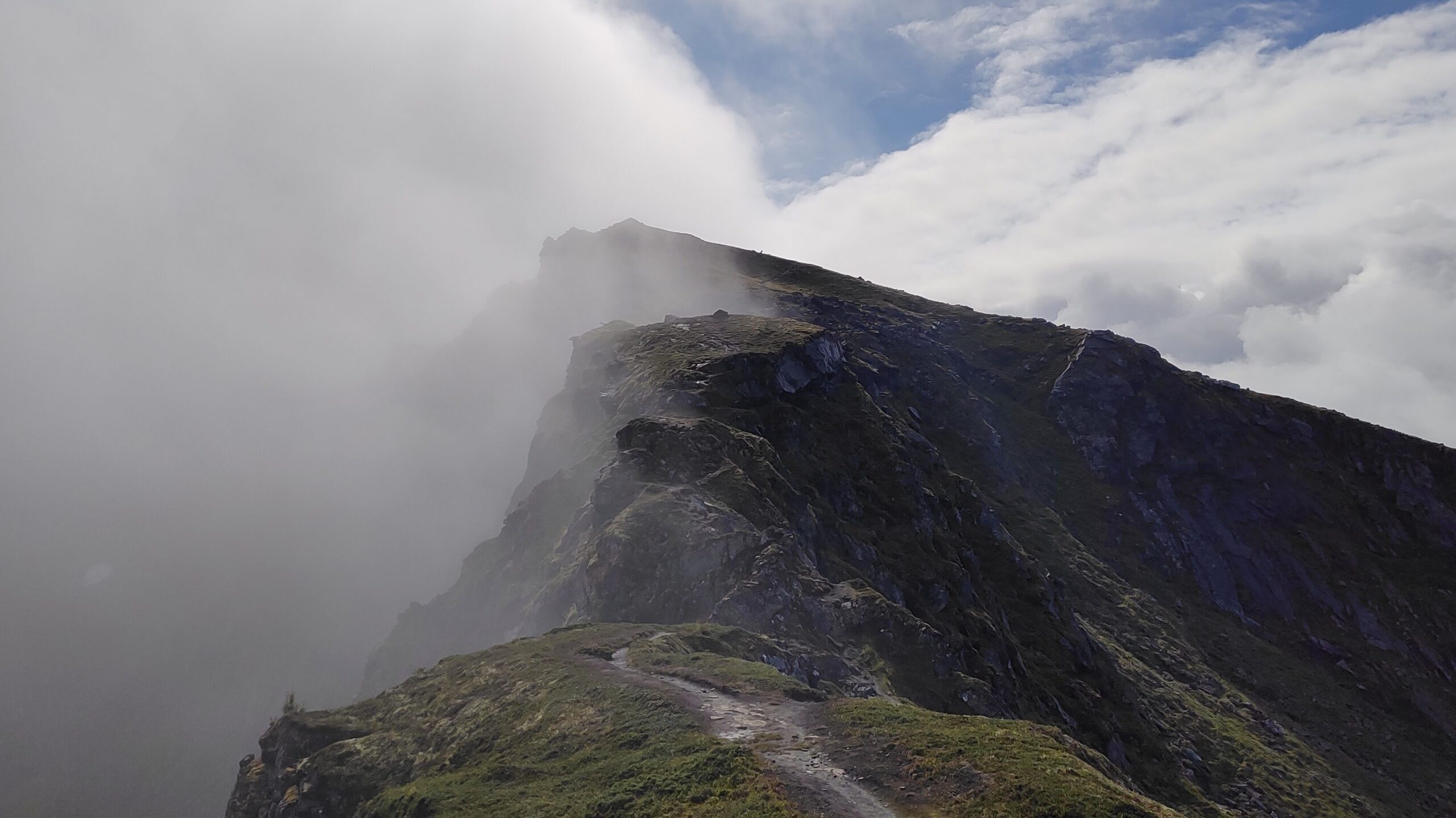 Mountain ridge on the Long Lofoten Trail, Lofoten Islands, Norway, with a hiking path disappearing into the clouds.