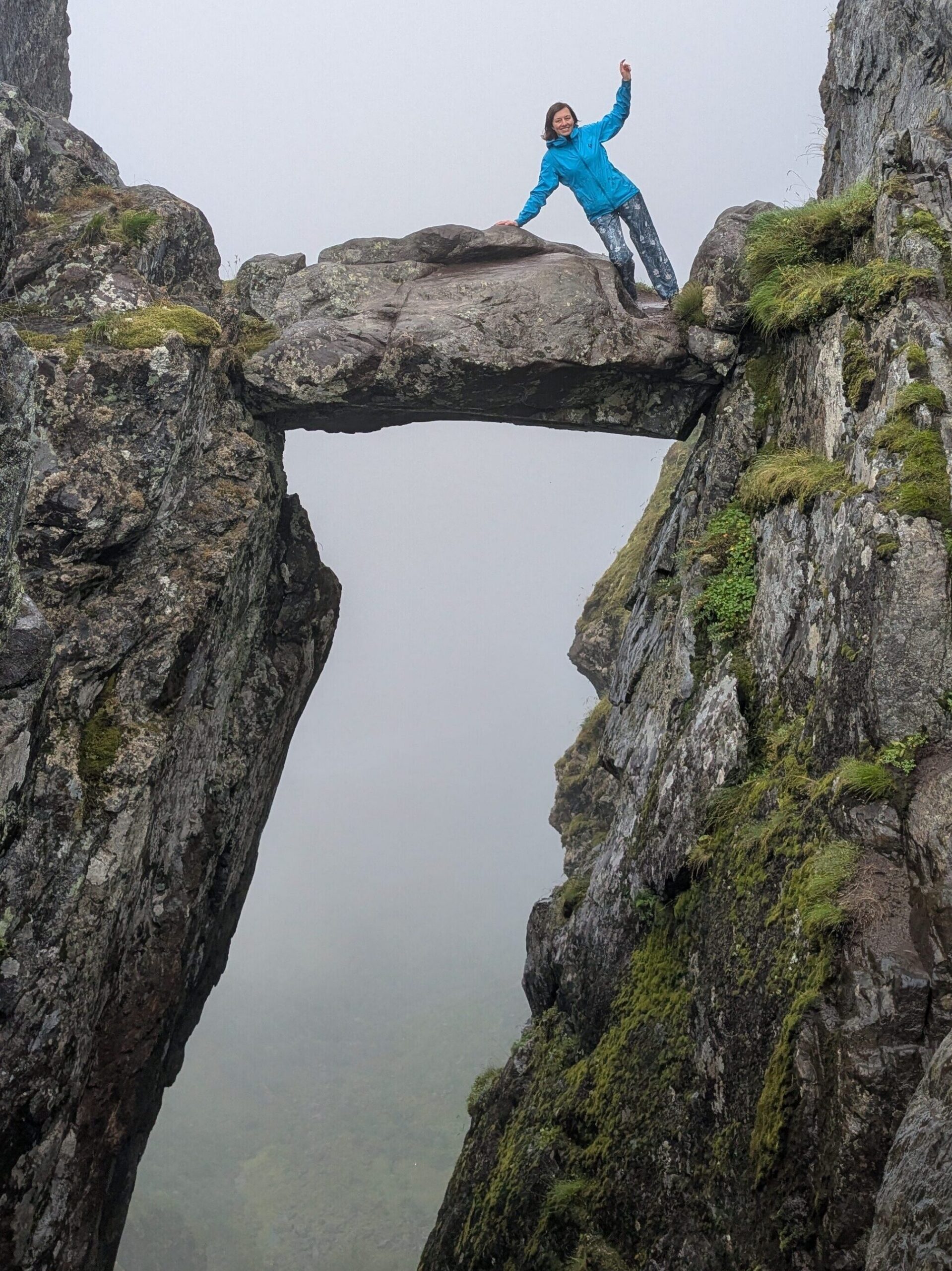 Hiker standing on Djevelporten (Devil's Gate), the iconic rock formation on the Fløya hike in the Lofoten Islands.