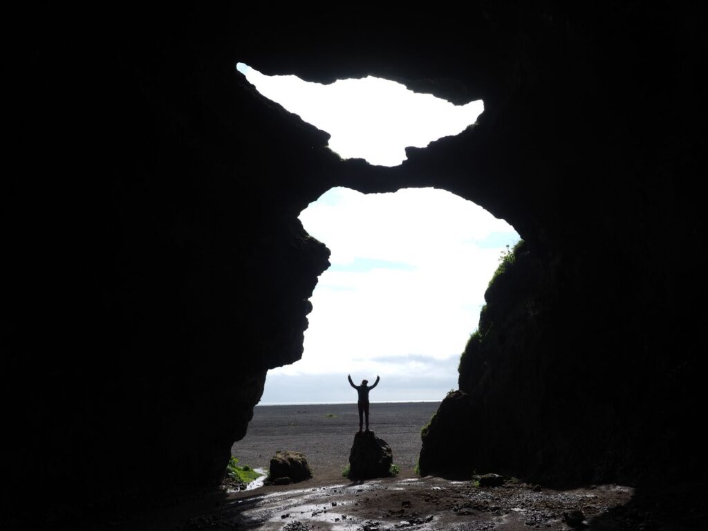 Silhouette of a person standing inside Yoda Cave (Gígjagjá) on Iceland's South Coast.