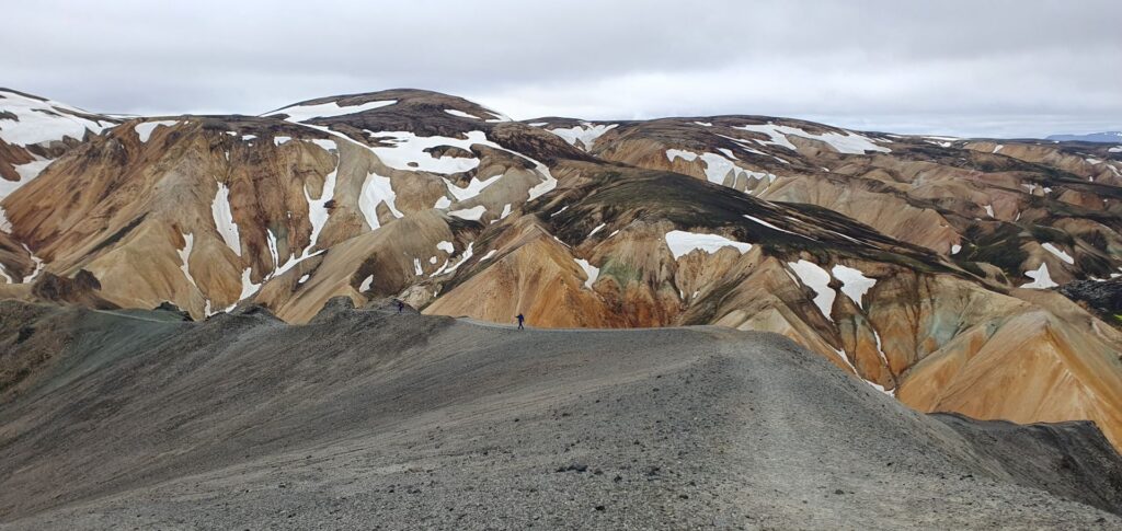 Panoramic view of black lava fields, colorful mountains and volcanic valleys along the Laugavegur Trail in Iceland.