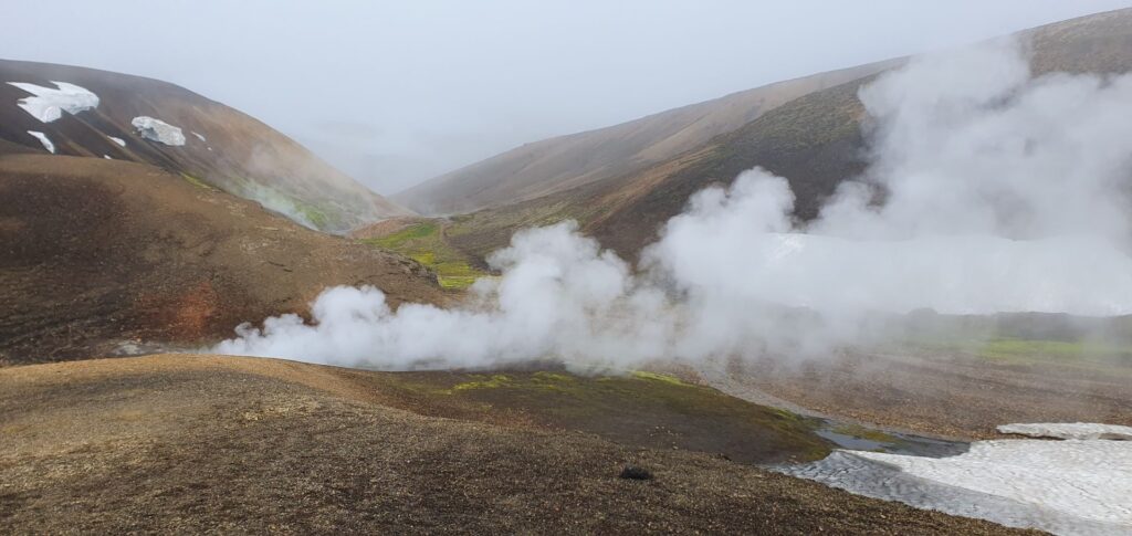Steam rising from geothermal vents in a volcanic valley along the Laugavegur Trail near Landmannalaugar.