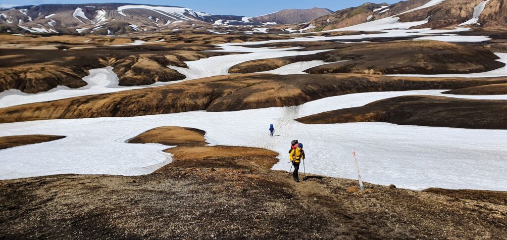 Hiker walking across snowfields on the Laugavegur Trail in the Icelandic Highlands.