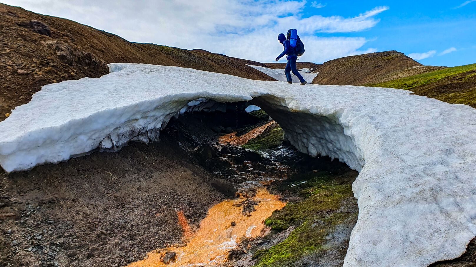 a person with heavy backpack crossing the snow bridge,Laugavegur Trail, Iceland