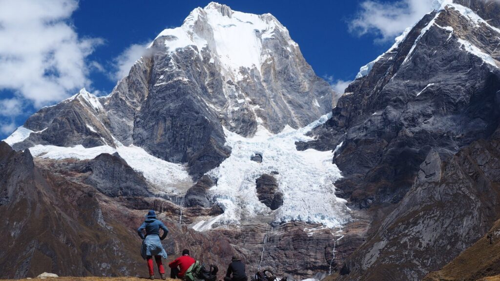 Siula Grande rising above Laguna Jahuacocham three persons looking at its majesty